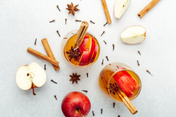 Spiced apple cider in glasses with cinnamon sticks, star anise, cloves, and apple slices. © reddish