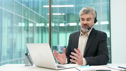 Confident businessman in a headset talking on a video call conference using laptop in office. Manager has a business meeting. Coach has online training, consultation, class, course or webinar remotely - Powered by Adobe