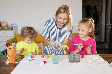 Happy family painting together. Young mother learn her little children to draw. Family art therapy and having fun time at home.