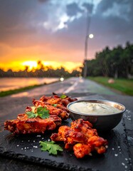 Grilled chicken wings on a stone plate outdoors at sunset