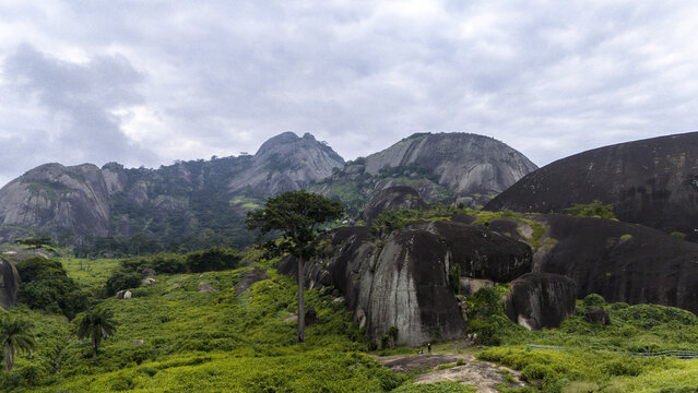Aerial view of the ancient Idanre Hills standing majestically against the sky, with lush greenery contrasting with the rugged rock formations, Ida really, Ondo, Nigeria.