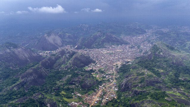 Aerial view of the majestic Idanre Hills embrace a sprawling town in a verdant valley, a tapestry of earth tones against the lush greenery, Ida really, Ondo, Nigeria.
