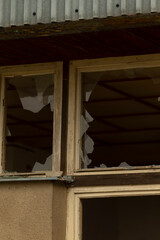 There is a broken window located on the side of a building that has experienced some form of damage or wear, disrupting its integrity