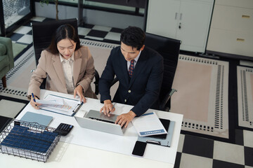 Business team analyzing documents, graphs, and data with a laptop, tablet, and smartphone. Collaboration, strategy, and success.