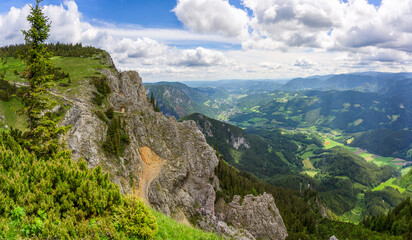 A stunning panoramic view of the Rax Mountains showcasing vibrant green valleys and rugged cliffs