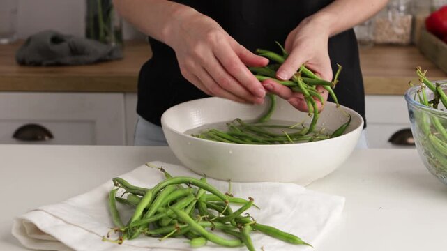 hands washing green beans in bowl and put on linen table