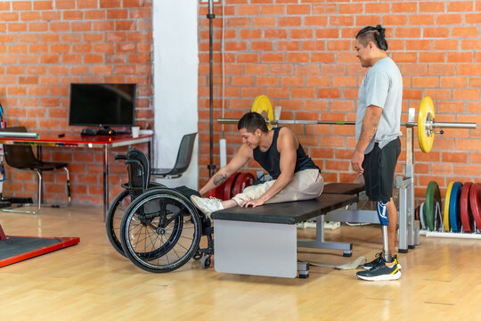 Disabled men exercising in gym using wheelchair and prosthetic leg - Powered by Adobe