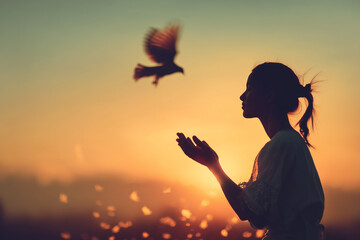 Silhouette of a woman releasing a bird into a vibrant sunset, symbolizing freedom, hope, and new beginnings. A serene and ethereal moment.