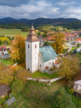Aerial view of the ancient church with its tall tower and copper roof, nestled amidst autumn trees, H&Atilde;&iexcl;j, &Aring;&frac12;ilina Region, Slovakia.