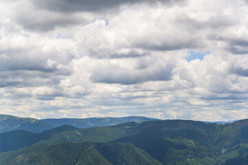Fototapeta premium A panoramic view showcasing the lush green mountains of Rax Austria under a vivid sky filled with clouds