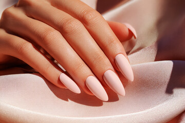 Hands with a classic French manicure are gently placed on luxurious, soft fabric. The delicate pink polish contrasts beautifully with the white tips, creating an elegant look