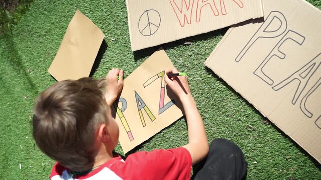Young activist boy drawing peace protest signs in spanish