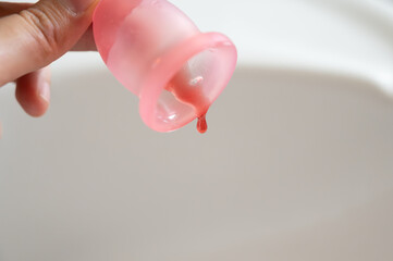 Hand holding menstrual cup dripping blood