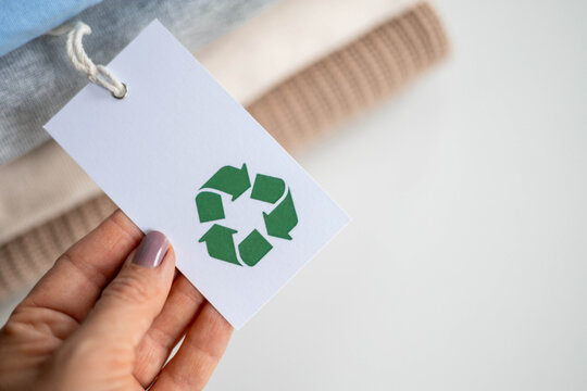 Eco tag with green recycle symbol on sustainable clothing stack for eco-friendly fashion