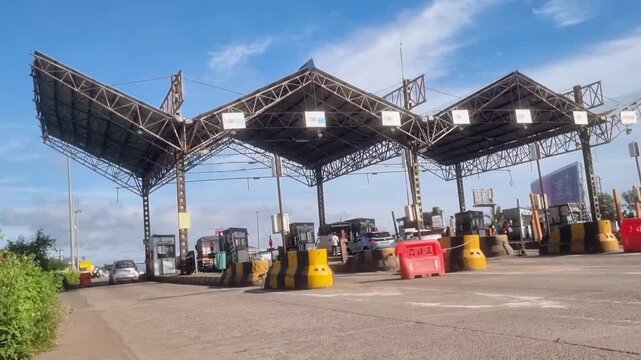 A toll plaza has a distinctive canopy with tensile architecture, a design that uses steel cables and membranes to create an aesthetically pleasing and functional structure over the booths.
