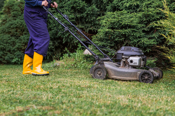The concept of gardening and country life. A lawn mower man mows the grass in the backyard. Agricultural machinery for garden maintenance. The banner.