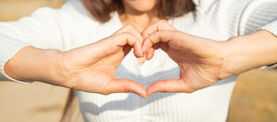 Caucasian girl making a heart shape in nature.