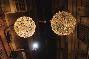 Two lighted spheres hanging from a wire. One is larger than the other. The wire is attached to a...