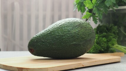 Fresh ripe avocado on the table for making a healthy breakfast or lunch. Avocado on the wooden table with different vegetables on the background