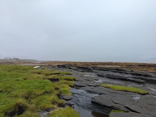 Layered rock pools and grassy shoreline at Broadford on the Isle of Skye Scotland