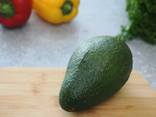Fresh ripe avocado on the table for making a healthy breakfast or lunch. Avocado on the wooden table with different vegetables on the background