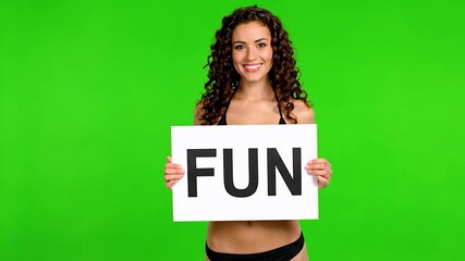 Smiling woman holding fun sign with green background and casual summer outfit green screen video - Powered by Adobe