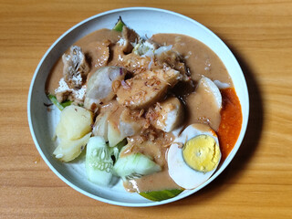 Gado Gado, traditional Indonesian vegetable salad with peanut sauce, chili sauce, lontong, tofu, cucumber, potatoes, and egg.