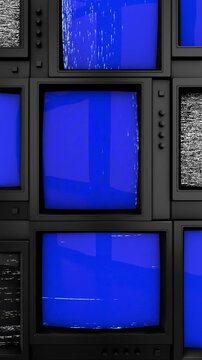 A wall of many old televisions. Retro televisions with blue chroma key screens and VHS static. A stack of television screens with blue screens. Vertical video. 9:16 format.
