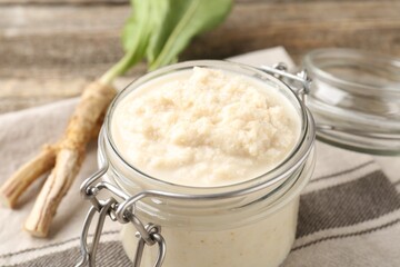 Tasty horseradish sauce and roots on wooden table, closeup