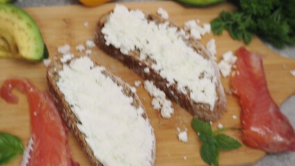 a woman cooks at home salmon and avocado sandwich cottage cheese or soft cheese whole wheat bread. keto diet food. recipe sandwich for the menu. takeaway food. proper nutrition diet for weight loss