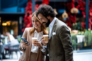 Business people using smartphone and drinking coffee outdoors