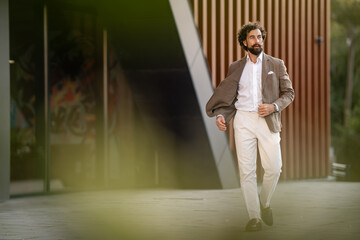 Fototapeta premium Confident businessman walking outside modern office building