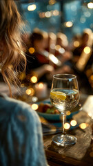Celebratory dinner party with soft lighting and a sparkling drink. The atmosphere is warm and inviting. Focus on refreshment.