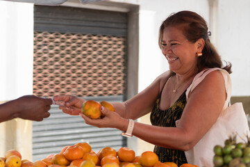 Obraz premium Woman buying oranges smiling at fruit market