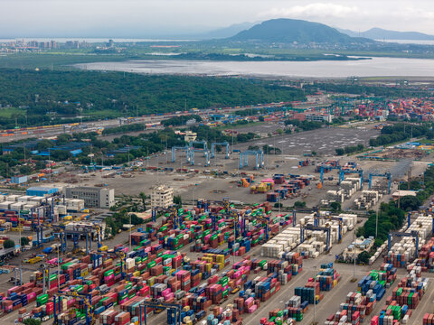 Aerial view of a sprawling port facility with stacks of colorful shipping containers contrasting against the industrial landscape, Nhava Sheva, Maharashtra, India.