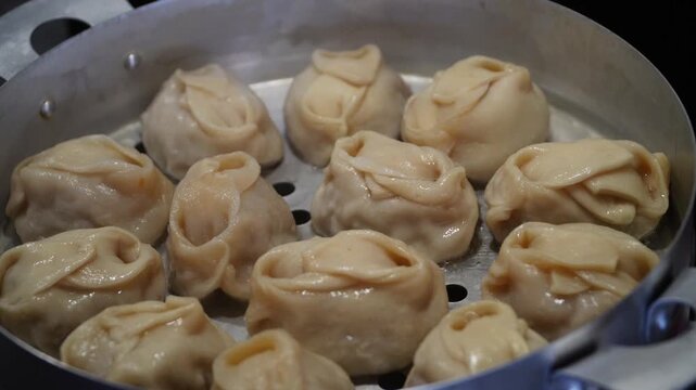 Delicious Manty, posture, khinkali is prepared in a special pot - mantoverde. Dishes of Asian, Buryat, Georgian cuisine. Aluminum steamer for cooking mantas on a stove in a home kitchen. Meat food.