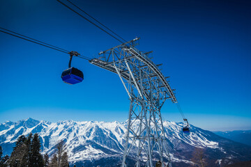 Gondola, cable car and ski lift with mountain, tree, blue sky on a sunny day at resort Krasnaya Polyana.