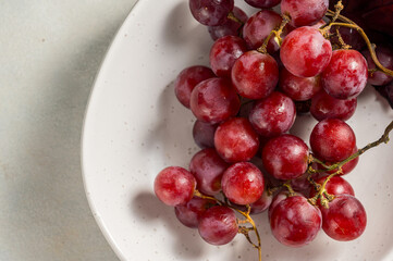 Pink grapes in a white plate, autumn harvest concept, copy space