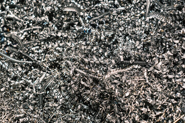 Close-up of metallic shavings and spirals, recycled metal waste from industrial machining process in factory workshop
