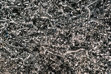 Shiny metallic machining shavings, close-up of curled steel swarf from industrial milling or turning processes in a workshop