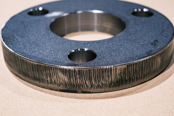 Close-up of round steel flange with drilled holes, precision-cut metal component for industrial engineering and manufacturing