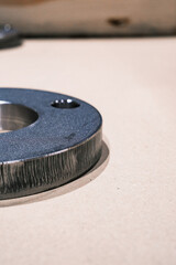 Close up of industrial metal ring component on beige surface, machined steel part for engineering and manufacturing background
