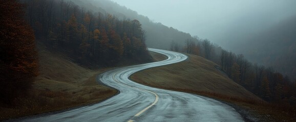 Serene Autumnal Road Winding Through Misty Mountains