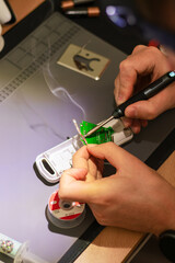 Soldering. A man is holding a solder to repair an electronic device. 