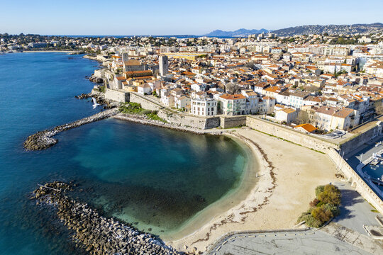 Aerial view of the sun-kissed Plage de la Gravette beach contrasting with the historic Chateau Grimaldi and the azure Mediterranean Sea, Antibes, Provence-Alpes-C&Atilde;&acute;te d'Azur, France.