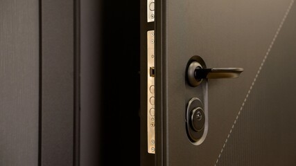 Obraz premium Modern dark gray metal front door slightly ajar, showing the multi-point locking system and handle, emphasizing security and privacy