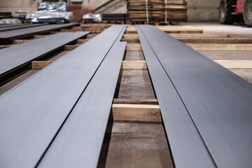 Long steel sheets in industrial workshop, stacked metal plates for construction and manufacturing use