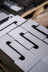 Stack of precision-cut steel plates with uniform slots, industrial metal components for manufacturing and engineering