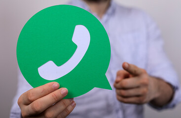 Person holding a WhatsApp logo.  Customer service, communication, contact.