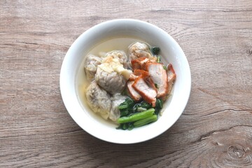 Chinese dumpling topping slice red barbecue pork with clear soup on bowl